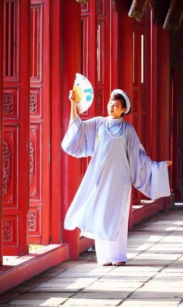 Hue, Vietnam - 24 Şubat 2023: Genç Vietnamlı bir kadın Hue, Vietnam 'daki Imperial City' de geleneksel elbiseler içinde poz veriyor. Geleneksel ao dai elbisesini giyen ziyaretçiler Kraliyet Şehri 'ne ücretsiz giriş hakkı kazandılar..