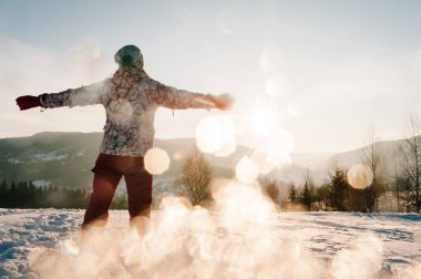 Kız geri çekilip karlı kış dağlarına bakıyor. Manzaranın tadını çıkarıyor. Doğada yürü. Buz mevsimi. Tatil konsepti. Dağlarda gezmek.