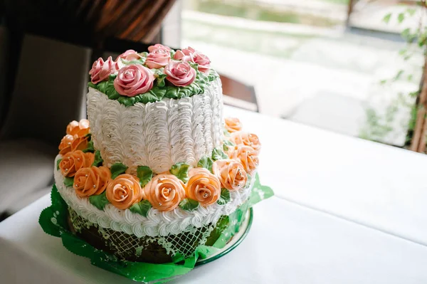 White wedding cake with pink flowers and greens on a festive table with pastry. close up of cake. Sweet table.