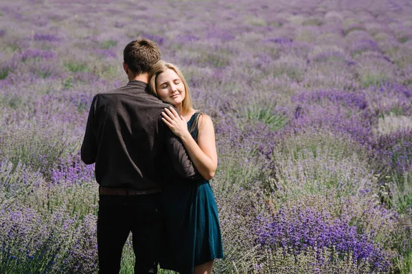 Back view lovely young couple in love in purple lavender field hugging and have romantic time. Man and woman in the flower fields. Honeymoon trip. Newly married. Happy couple travel. Lavender meadows.
