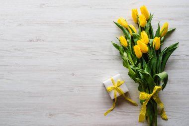 Bouquet of tulips with gift box on white wooden background. Space for message. Flowers concept. Holiday greeting card for Valentine's, Women's, Mother's Day, Easter. Birthday. Top view, flat lay.