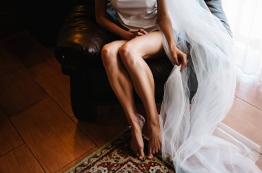 Bacakların alt tarafına bakınca, gelin seksi iç çamaşırları ya da geceliğiyle evdeki koltukta oturuyor. Sabah bir düğüne hazırlanıyorum..