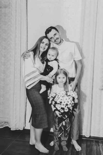 有两个孩子的快乐的年轻家庭 女儿和儿子在家里拥抱在一起 有小孩的有爱心的父母 家庭日 黑白照片 — 图库照片