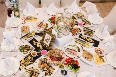 Bir etkinlik için bir restoranda şenlikli bir masa hazırladık. Soğuk mezeler ve tabaklar düğün masasında. Üst Manzara. Kapat..