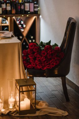 Gece sürpriz evlilik teklifi için büyük bir buket kırmızı gül. Lüks romantik randevu. Dekorasyon, yanan mumlar. Etkinlik için restoranda masa ayarlandı. Sevgililer gününde çiftler için mum ışığı.