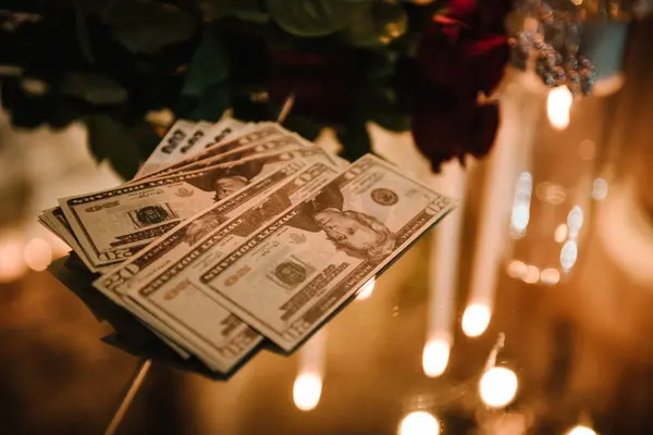 Dollars and Euros, a pile of banknotes lies on the table. Style table on background of evening lighting in restaurant for gala dinner. Mirror table for party. Flowers and money for wedding invitations