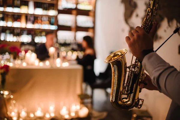 Saxophonist\'s hands while playing jazz. Musician hold sax at romantic date on Valentine\'s Day in restaurant. Man performing on saxophone at party or wedding. Jazz music concept closeup. Space for text