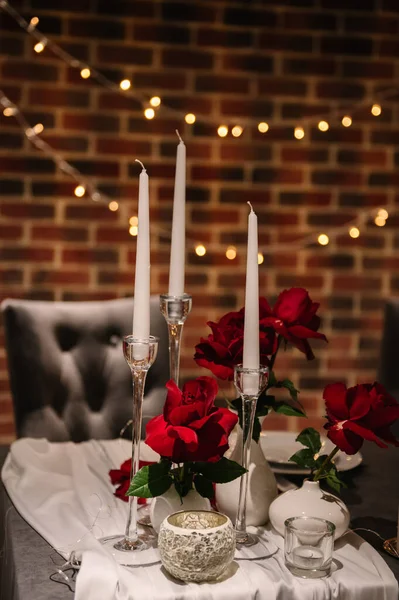 Luxurious decor for event with garland. Detail decor. Table decorated with tablecloth with flowers, candles. Romantic dinner by candlelight. Marriage proposal. Set up couple on evening Valentine\'s day