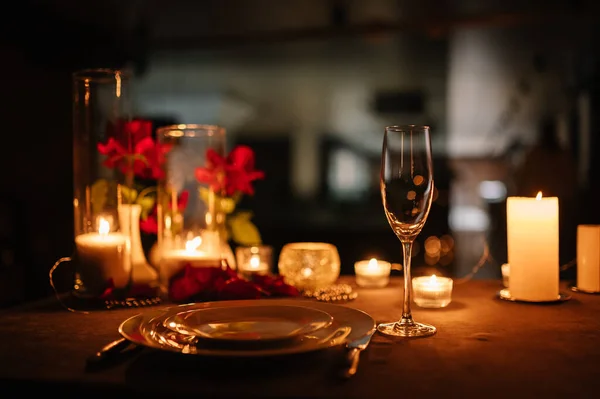 Candlelight date in restaurant. Champagne glasses, bouquet flowers. Romantic dinner setup at night. Table setting for couple, Valentine\'s Day evening, burning candles for surprise marriage proposal.