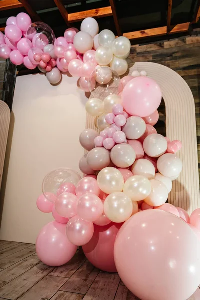 Beige photo wall decoration space or place for text with pink balloons. Arch with balloons for a party. Details closeup. Trendy decor. Birthday party. Celebration concept. Wedding reception.