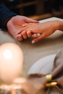 Nişan yüzüğüyle birkaç el. El ve kalp teklifi. Erkek kadına evlenme teklif ediyor. Lüks romantik randevu. Lokantada masa hazır. Sevgililer gününde çiftler için yemek masası.