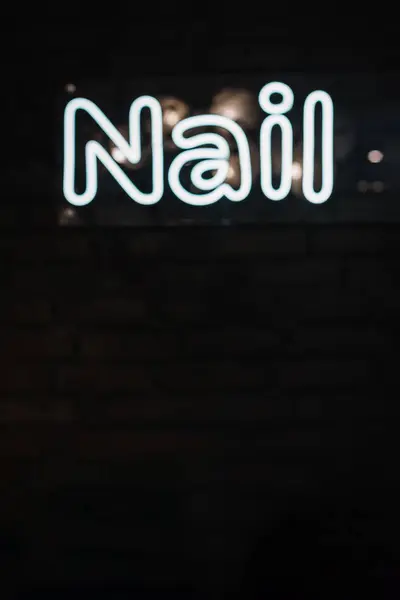 Nails. Neon electricity fluorescent sign Nail concept illuminated vintage manicure salon. Glow icon logo text light Nail on billboard or signboard. Closeup. Sign on a black background