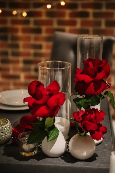 Table decorated with flowers, candles. Luxurious decor for event with garlands. Detail decor. Romantic dinner by candlelight. Surprise marriage proposal. Set up for couple on evening Valentine\'s day