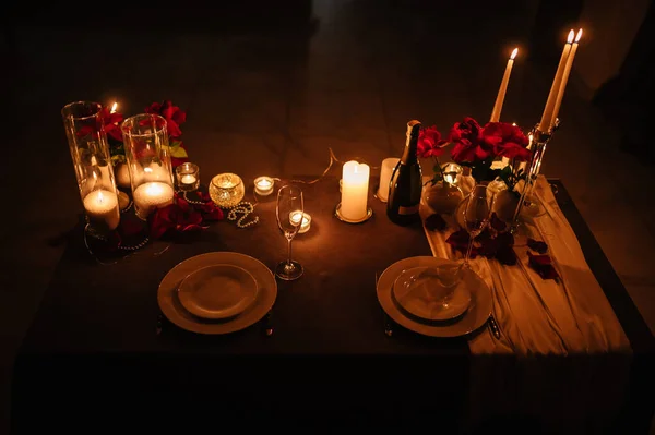 Location for surprise proposal at night. Decoration flowers, burning candles, details. Luxury romantic date. Table setting in restaurant for event. Candlelight for couple on Valentines day. Top view