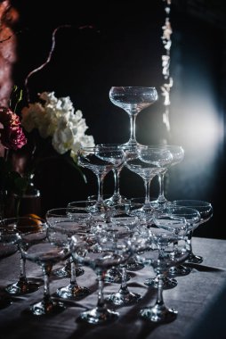 Bardaki kokteyller için bardaklar. Lezzetli bir düğün töreni. Şölende doğum günü partisi için masa süslemesi pembe çiçekler. Siyah arkaplanda çiçekler ve ışık olan bardaklar.