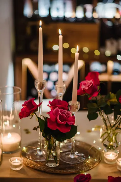 Luxury candlelight date in restaurant. Bokeh, garlands, bouquet flowers. Romantic dinner setup at night. Table set for couple, Valentine\'s Day evening, burning candles for surprise marriage proposal.