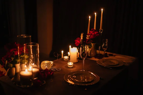 Candlelight date in restaurant. Champagne glasses, bouquet flowers. Romantic dinner setup at night. Table setting for couple, Valentine\'s Day evening, burning candles for surprise marriage proposal.