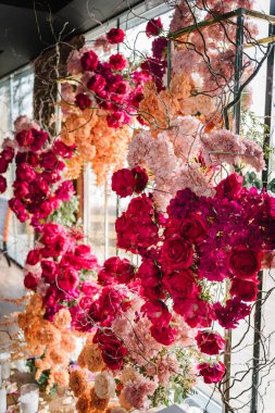 Kemerli pembe, turuncu çiçekli güller, doğum günü partisi için salon, şölen alanında. Lüks tören için düğün resepsiyonu. Etkinlik dekorasyonu. Dekorasyon ayrıntıları. Fotoğraf duvarı, kemer.