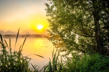 Sisin içinde nehrin üzerinde güzel bir gün doğumu.