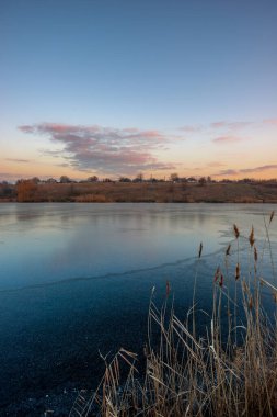 Açık bir kış akşamında gölün dikey görüntüsü.