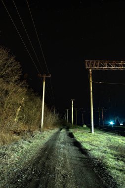 Demiryolu ve ışıkları olan gece yolu.