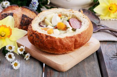 The sour rye soup inside loaf of bread. Easter breakfast table. Festive time