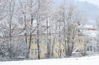An old building among frosted trees in the morning in the countryside. Beautiful winter day.