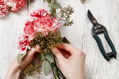 Çiçekçi iş başında. Buket kırmızı ve beyaz Karanfil çiçek yapma kadın.