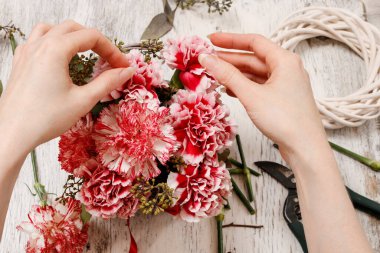 Çiçekçi iş başında. Buket kırmızı ve beyaz Karanfil çiçek yapma kadın.