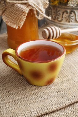 Tahta masada bir fincan çay ve bir kavanoz bal. Sağlıklı yemek.
