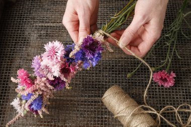 Çiçekçi iş başında. Vahşi çiçeklerle çelenk yapan kadın. Parti dekoru