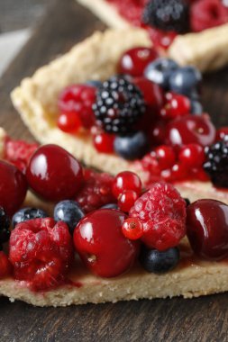 Böğürtlenli, böğürtlenli, yaban mersinli, kirazlı ve kırmızı üzümlü bir parça meyveli tart. Parti tatlısı