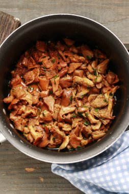 Cantharellus cibarius, bilinen adıyla chanterelle, Golden chanterelle veya Girolle. Büyük bir tencerede tereyağlı mantar. Sağlıklı yemek.