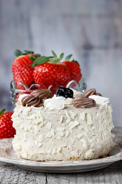 Round vanilla cake on cake stand. Fresh strawberries in the background. Party dessert