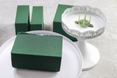 Kadın, bir buketi sabitlemek için iğne tutucuyu nasıl kullanacağını gösteriyor..