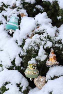 Geleneksel takılar bahçedeki bir Noel ağacına asılır. Açık hava dekorasyonları, dallarda kar..