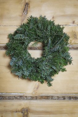 Ahşap bir duvarda köknar ağacından yapılmış büyük geleneksel Noel çelengi. Şenlik Dekoru