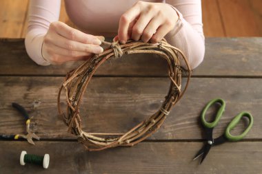 Florist at work: woman shows how to make a door wreath with dry flowers and orher plants. Step by step, tutorial. clipart