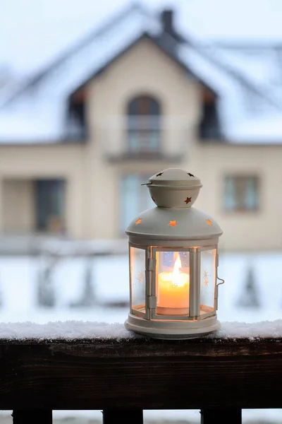 A beautiful lantern on a wooden porch. Family house in the background.