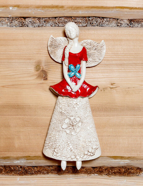 Фигура ангела висит на деревянной стене. Декор дома
