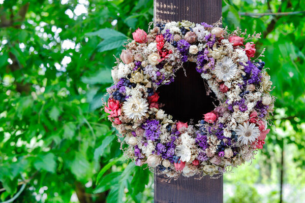 На крыльце висит красивый венок из сухих растений. Декор сада