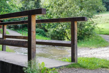 Karanlık ve boğucu bir ormana giden sığ bir dereden geçen ahşap bir köprü. Turistler için yol
