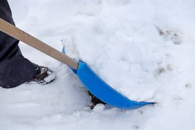 Adam kar fırtınasından sonra kaldırımdan karı kaldırıyor. Karlı kış günü