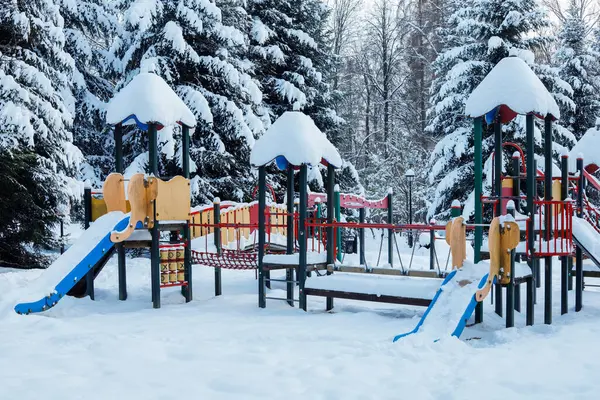 Şehir parkındaki çocuk parkı karla kaplı. Kış zamanı