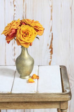 Altın vazoda bir buket turuncu gül. Ahşap arka plan. Ev dekoru