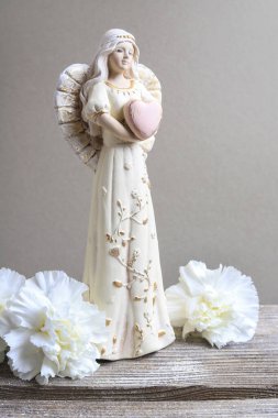 Seramik melek figürü ve tahta masada beyaz çiçekler. Düğün dekorasyonu. El yapımı.