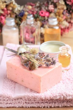 Gül ve lavanta rengi el yapımı sabun ve pembe havlu. Arka planda başka kozmetikler de var. Spa zamanı