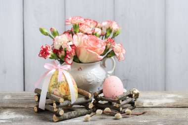 Paskalya süslemesi boyalı yumurta ve bir buket çiçekle. Şenlikli parti dekorasyonu