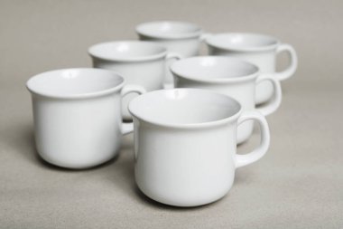 Gri kağıt arka planda beyaz porselen kupalar. Grafiksel kaynaklar