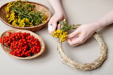 Kadın, Rowan Berry ve Tansy ile sonbahar kapısı çelengi yapmayı gösteriyor. Adım adım, öğretici.